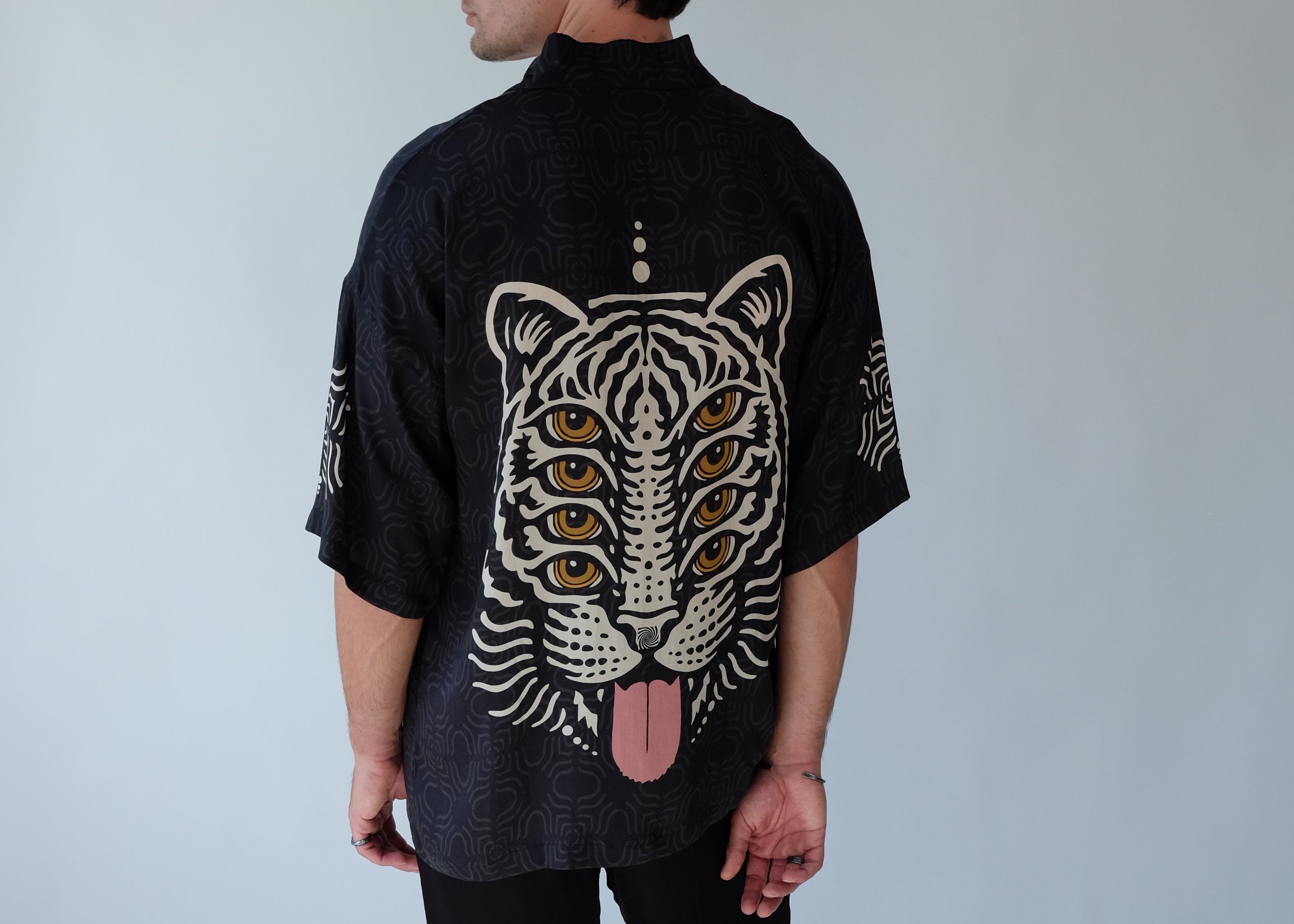 Person wearing a black jacket with a white tiger design on a light gray background