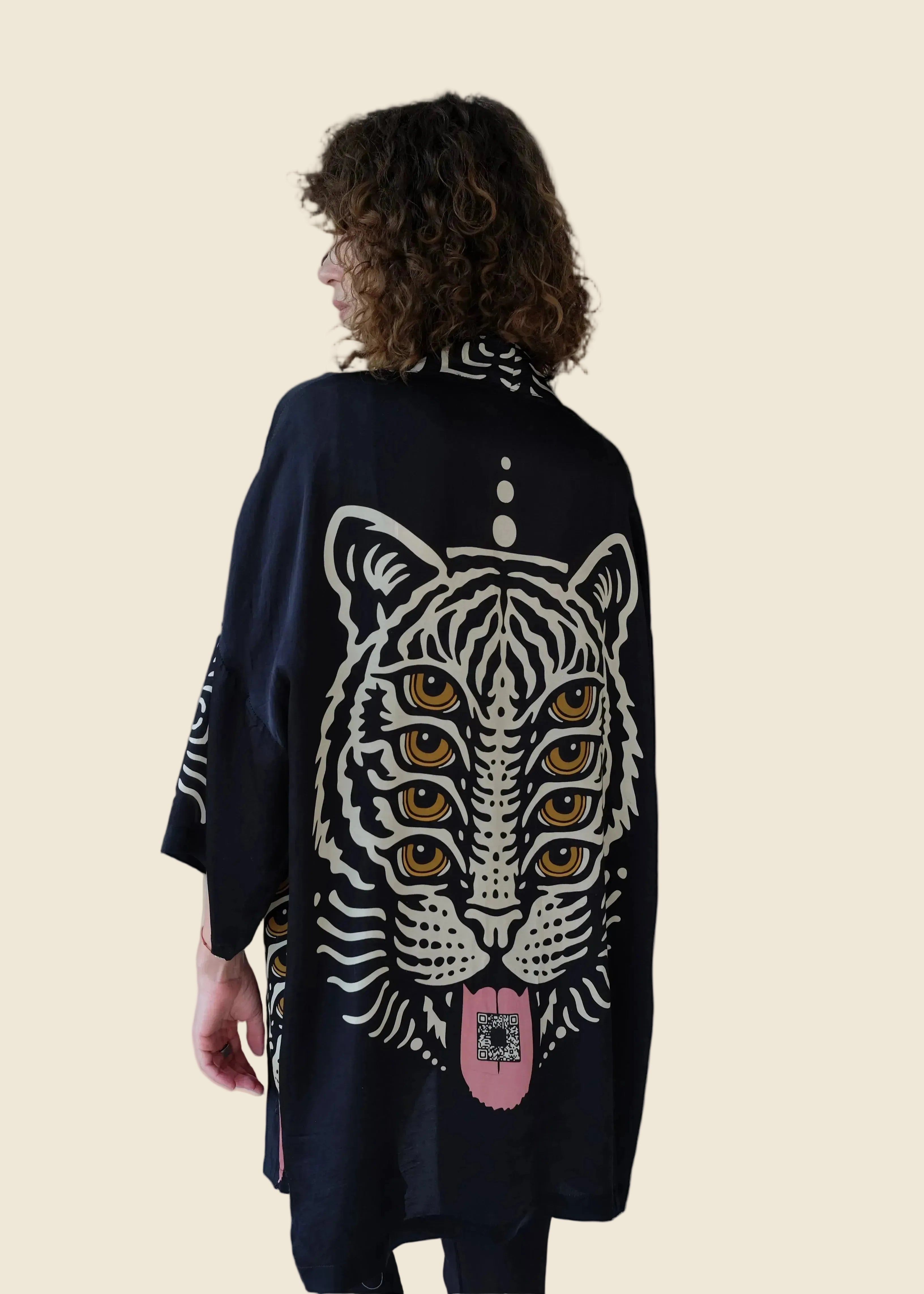 Person wearing a black jacket with a white tiger design on a light gray background